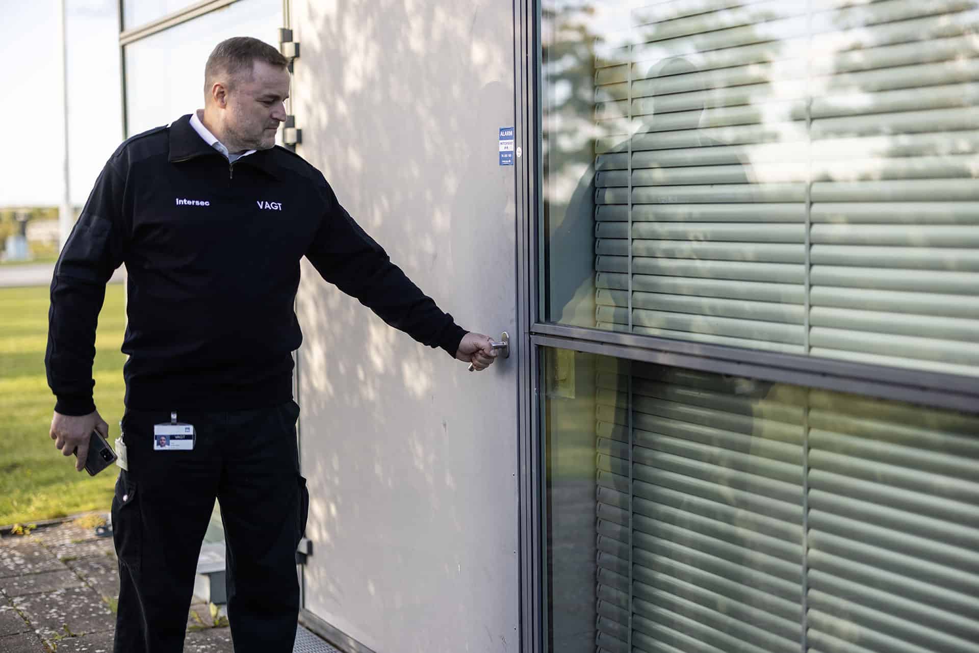 Sikkerhedsvagt låser op eller låser dør til kontorbygning.